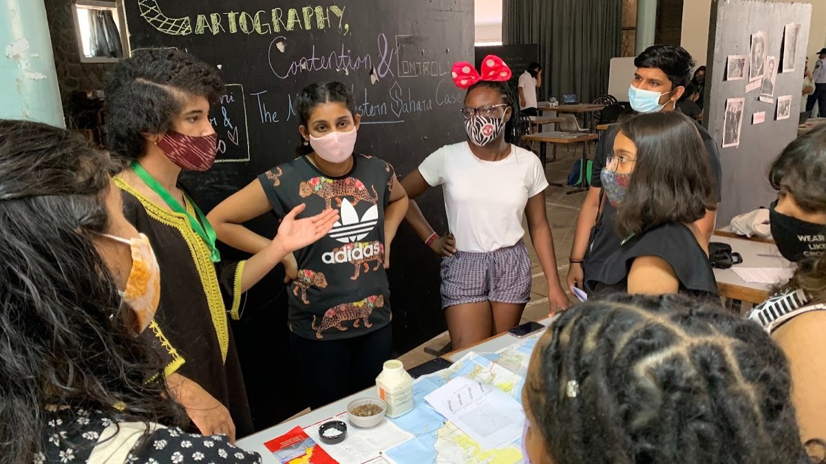 Students gathered around a table of maps and documents, presenting a case on the Western Sahara